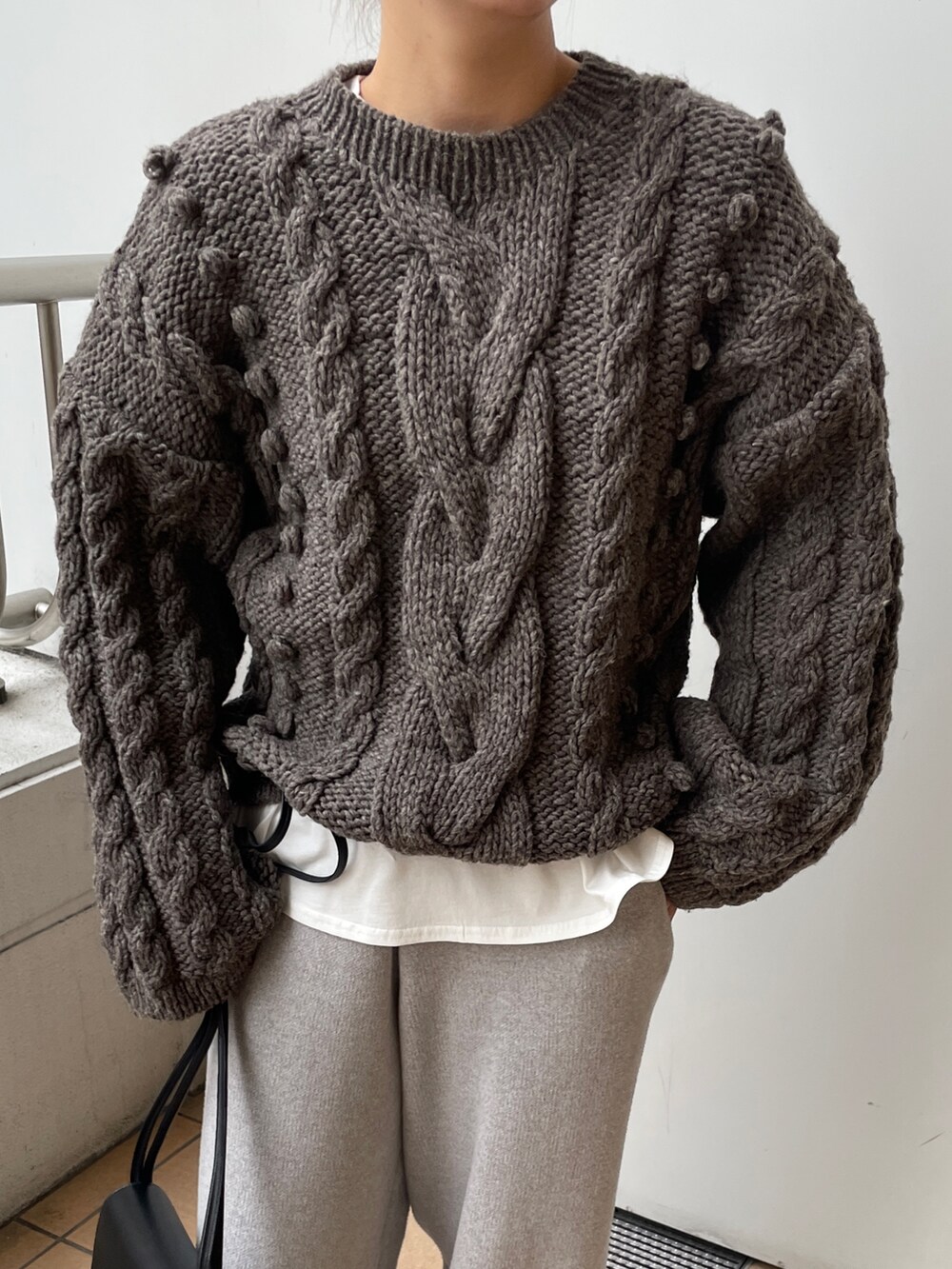 ブラック系のチェスターコート、グレー系のその他パンツ、ブラック系のハンドバッグを着用したレディースの冬コーディネートの7枚目の写真