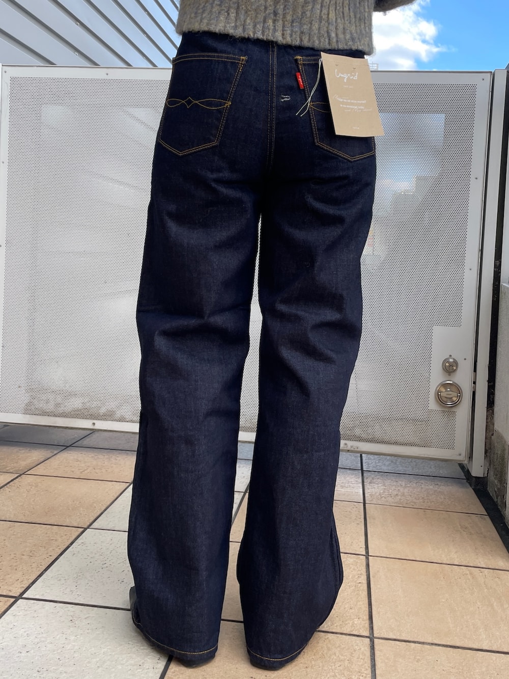 グレー系のニット/セーター、ブルー系のデニムパンツ、ブラック系のネックレスを着用したレディースの秋コーディネートの9枚目の写真