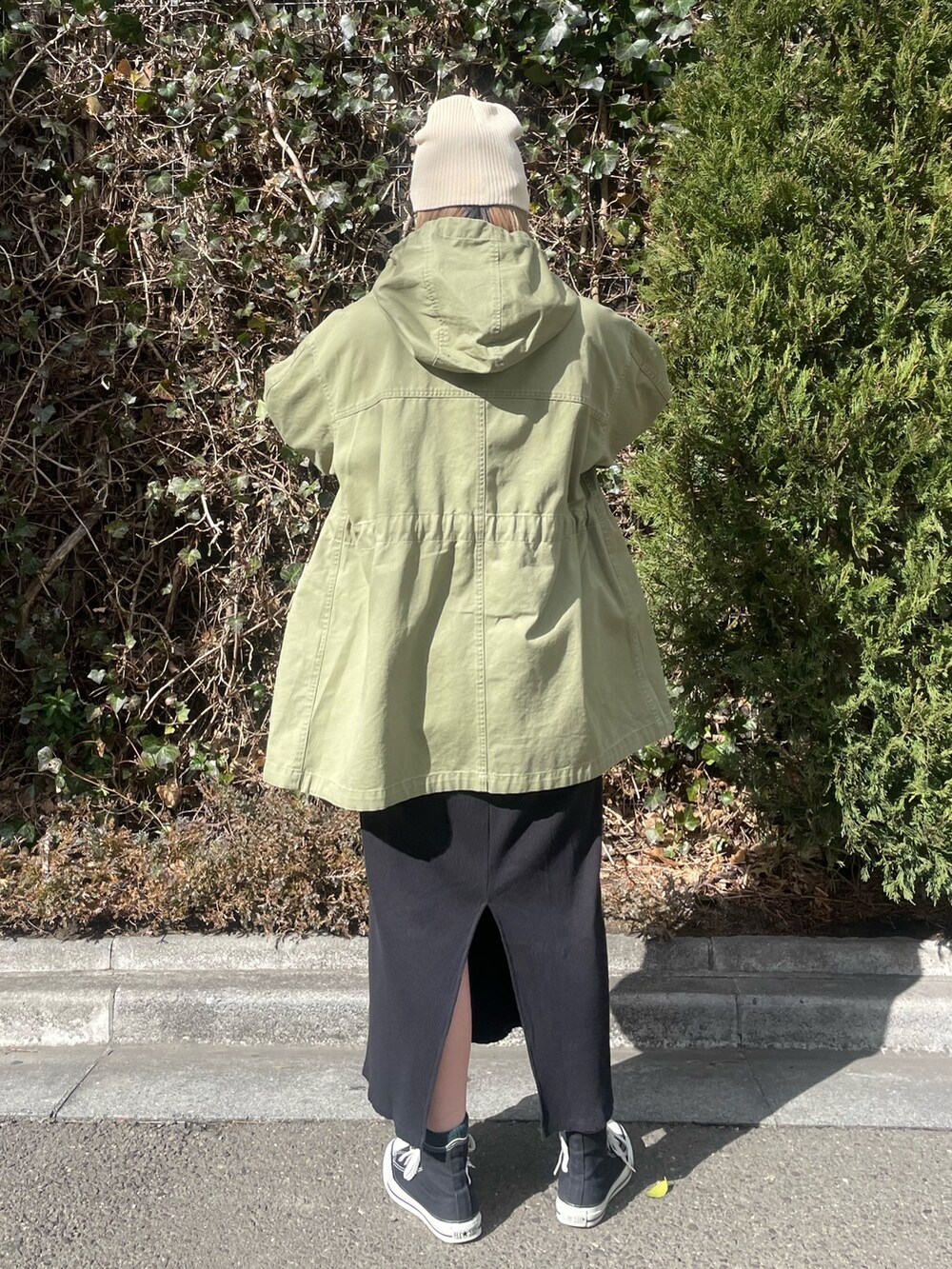 グリーン系のブルゾン、ブラック系のワンピース、ホワイト系のニットキャップ/ビーニーを着用したレディースの冬コーディネートの4枚目の写真