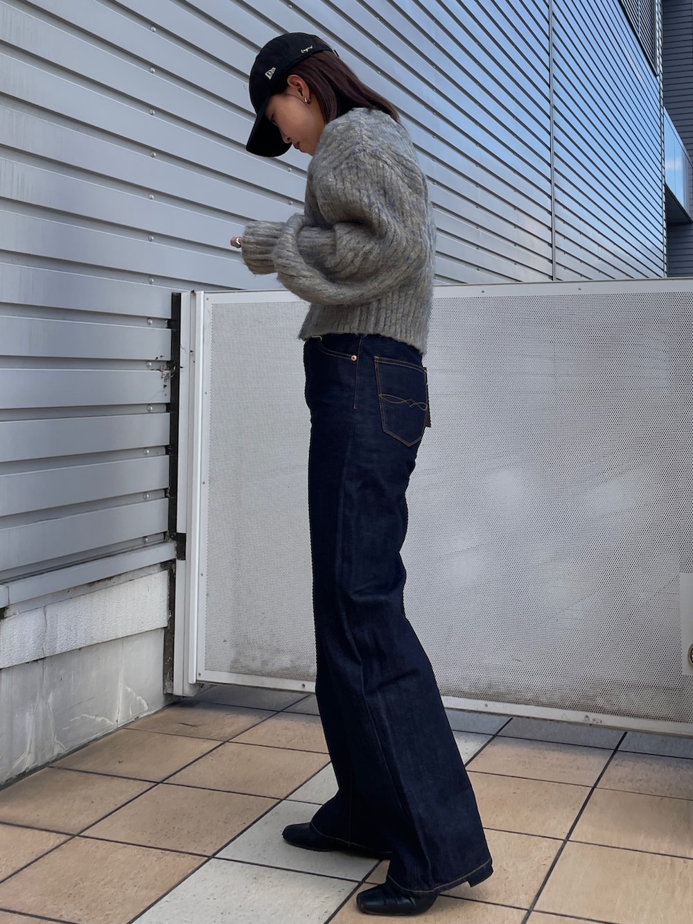 グレー系のニット/セーター、ブルー系のデニムパンツ、ブラック系のネックレスを着用したレディースの秋コーディネートの2枚目の写真