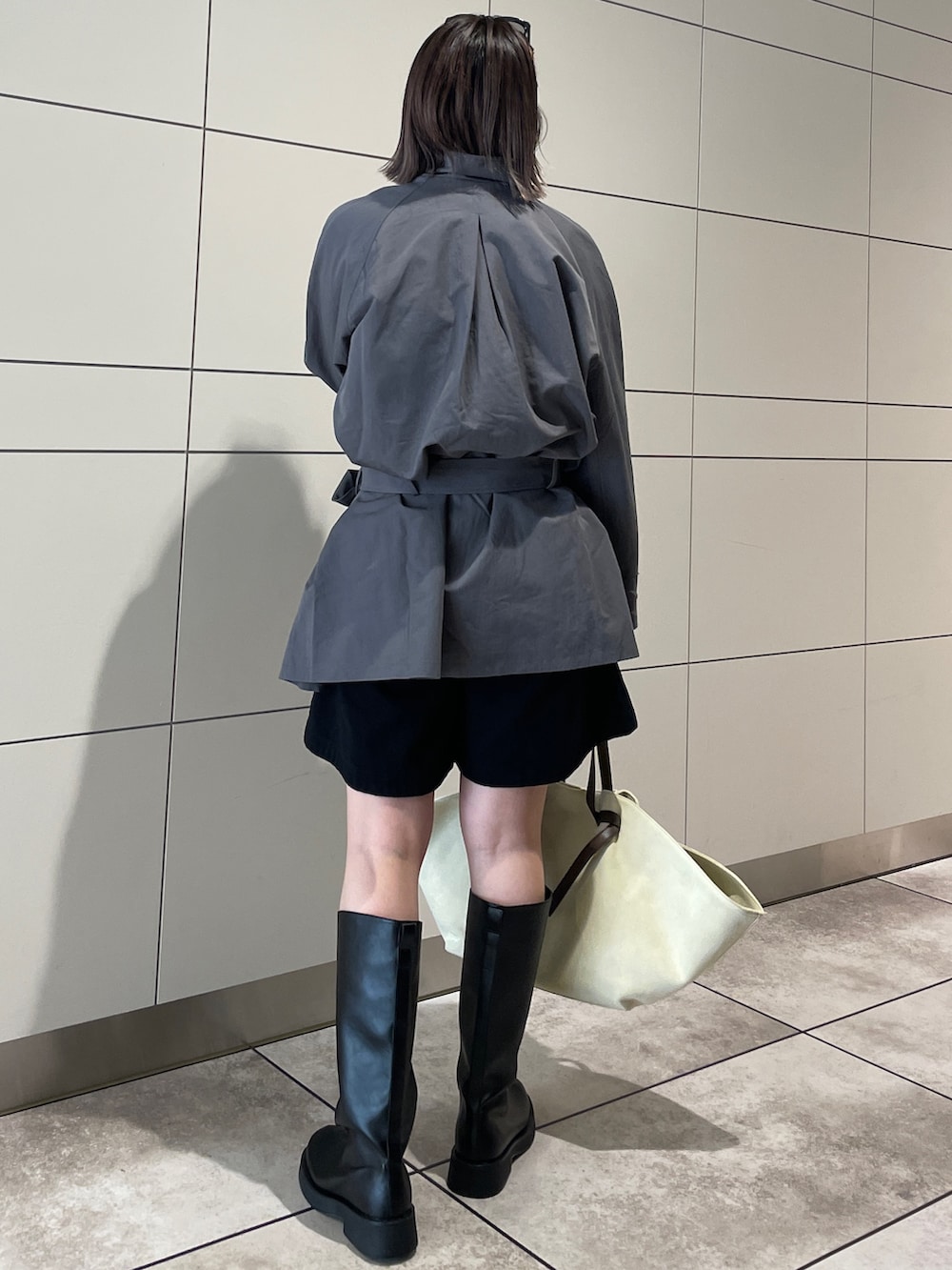 グレー系のトレンチコート、ブラック系のその他パンツ、ブラウン系のトートバッグを着用したレディースの冬コーディネートの3枚目の写真