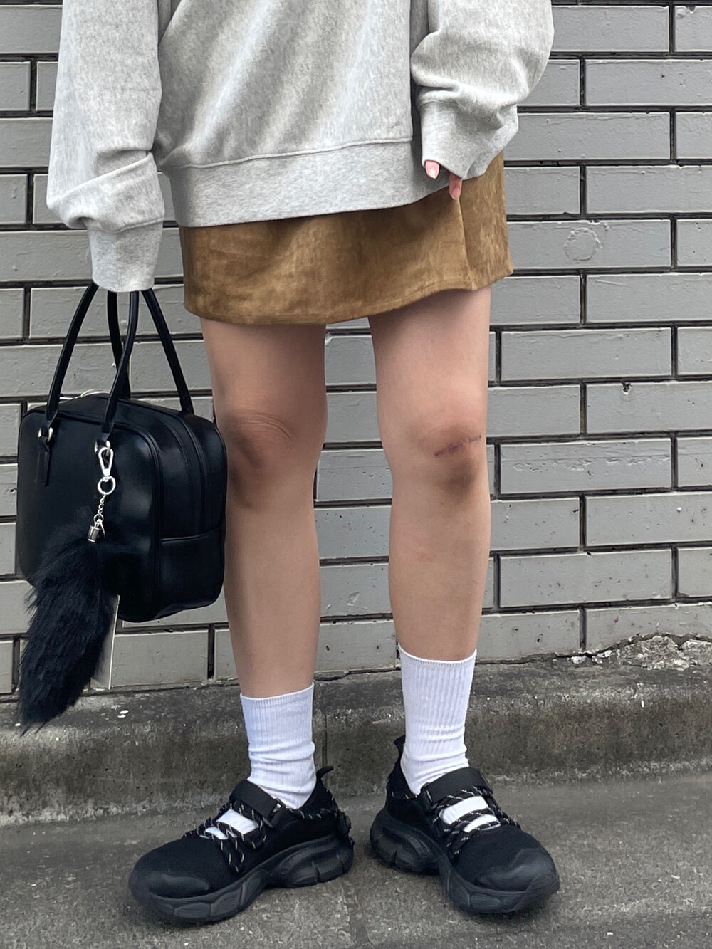 グレー系のスウェット、ベージュ系のスカート、ブラック系のハンドバッグを着用したレディースの秋コーディネートの5枚目の写真