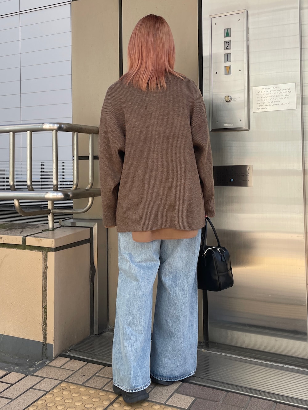 ブラウン系のカーディガン/ボレロ、ブルー系のデニムパンツ、ブラック系のハンドバッグを着用したレディースの秋コーディネートの5枚目の写真