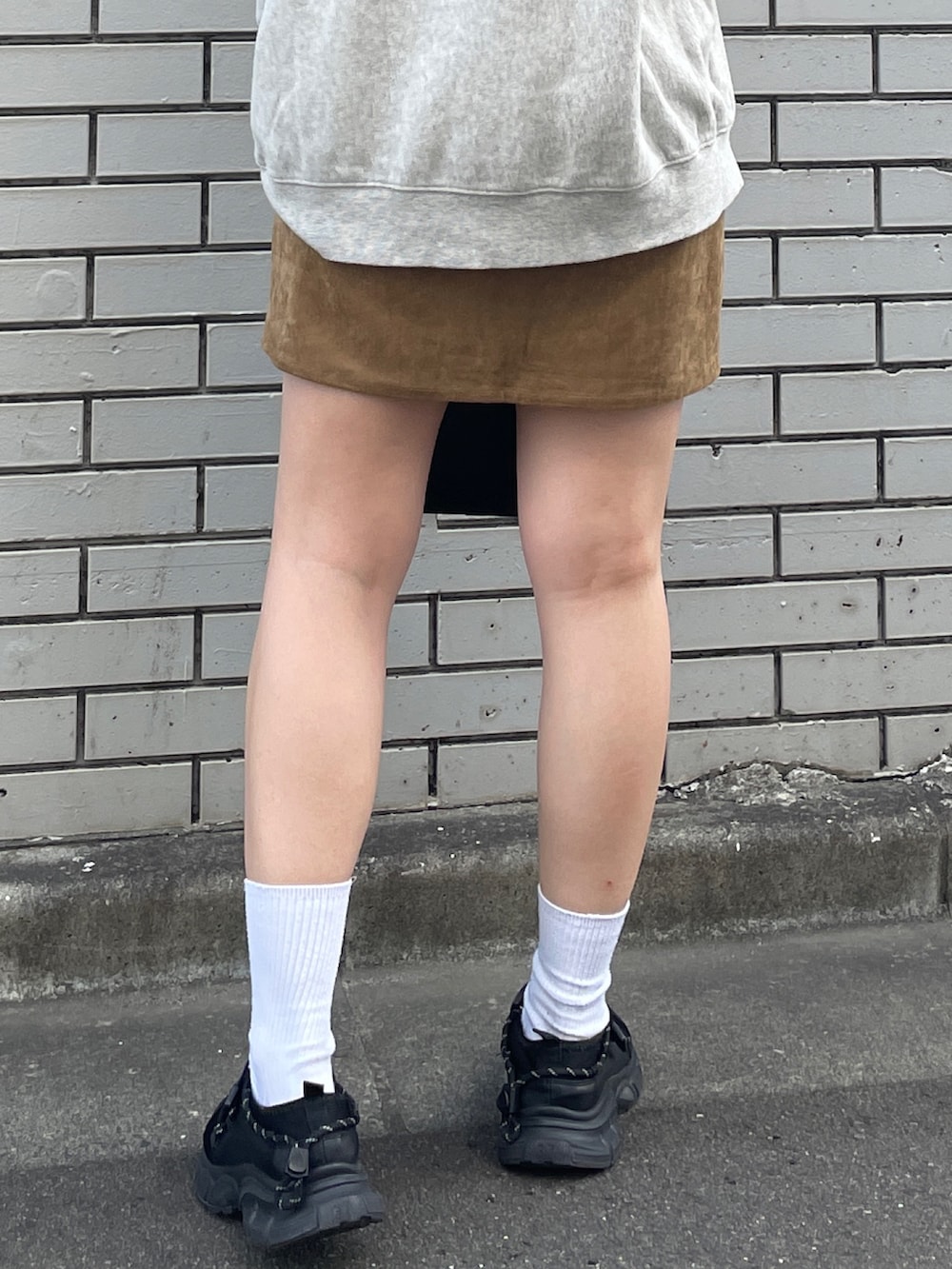 グレー系のスウェット、ベージュ系のスカート、ブラック系のハンドバッグを着用したレディースの秋コーディネートの7枚目の写真