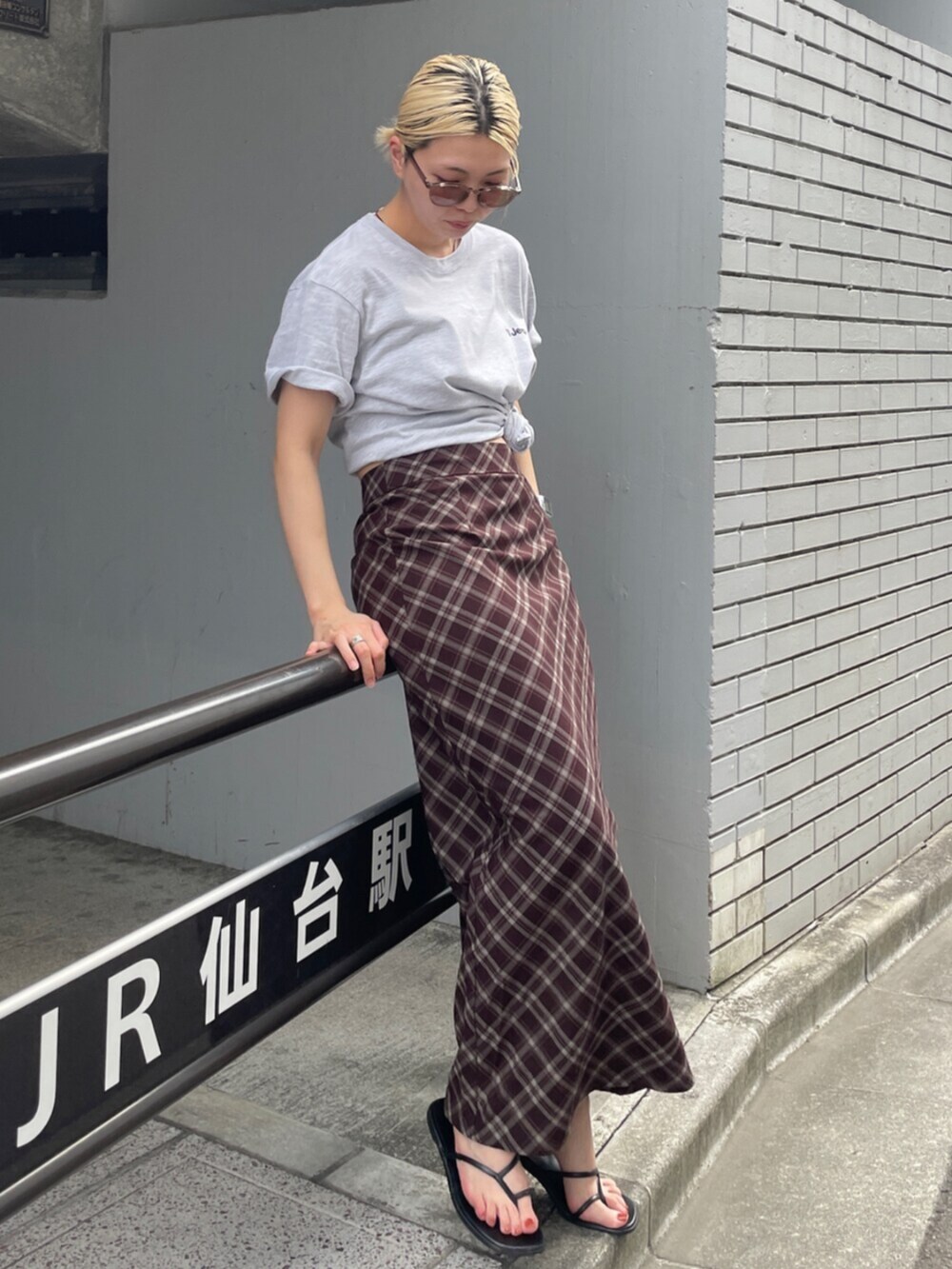 ブラウン系のスカート、グレー系のTシャツ/カットソーを着用したレディースの夏コーディネートの2枚目の写真