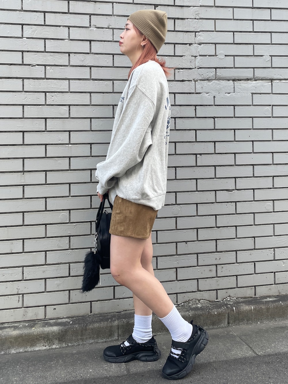グレー系のスウェット、ベージュ系のスカート、ブラック系のハンドバッグを着用したレディースの秋コーディネートの2枚目の写真