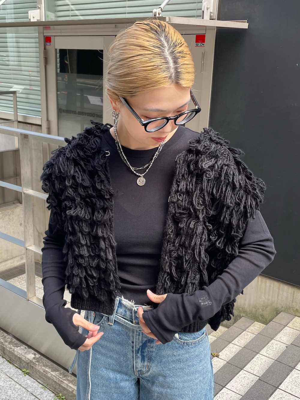 ブルー系のデニムパンツ、ブラック系のベスト、ブラック系のTシャツ/カットソーを着用したレディースの秋コーディネートの5枚目の写真