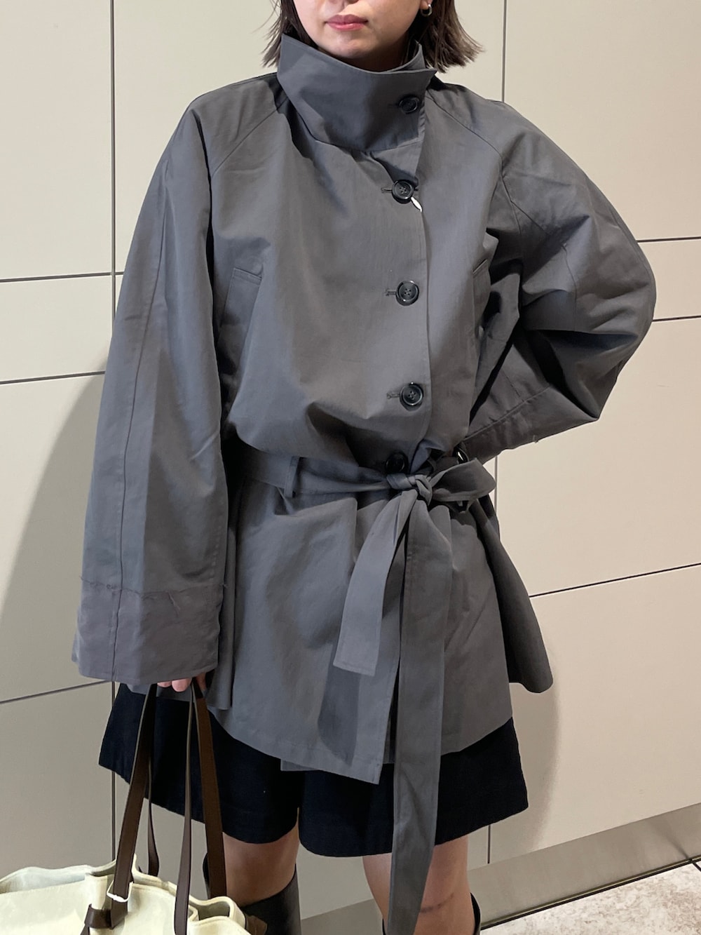 グレー系のトレンチコート、ブラック系のその他パンツ、ブラウン系のトートバッグを着用したレディースの冬コーディネートの4枚目の写真