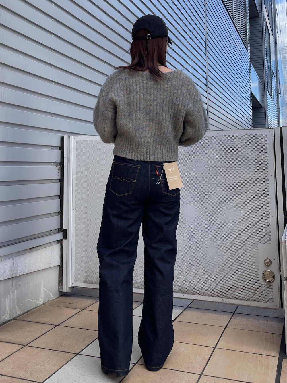 グレー系のニット/セーター、ブルー系のデニムパンツ、ブラック系のネックレスを着用したレディースの秋コーディネートの3枚目の写真