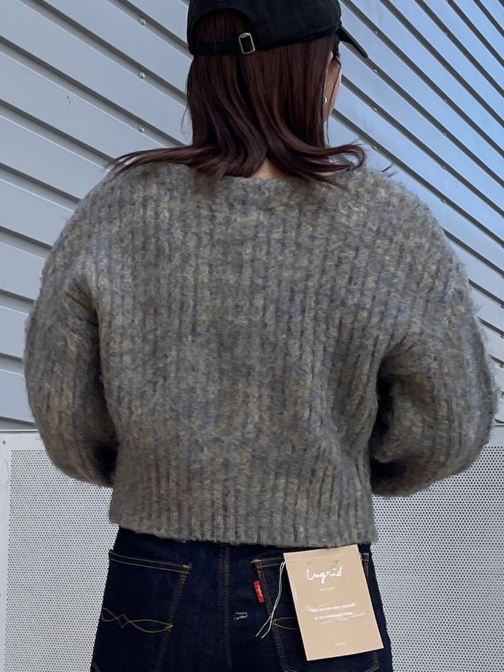 グレー系のニット/セーター、ブルー系のデニムパンツ、ブラック系のネックレスを着用したレディースの秋コーディネートの6枚目の写真