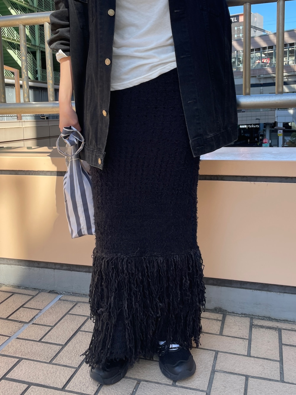 ブラック系のデニムジャケット、ホワイト系のTシャツ/カットソー、ブラック系のスカートを着用したレディースの秋コーディネートの5枚目の写真