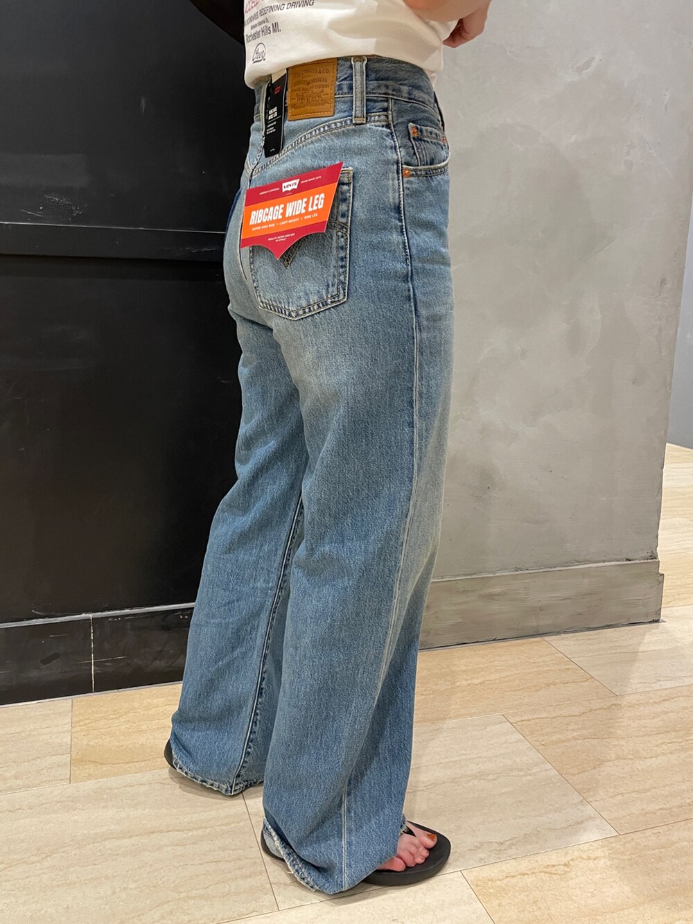 ブルー系のデニムパンツ、ホワイト系のTシャツ/カットソー、ブラック系のハンドバッグを着用したレディースの夏コーディネートの7枚目の写真