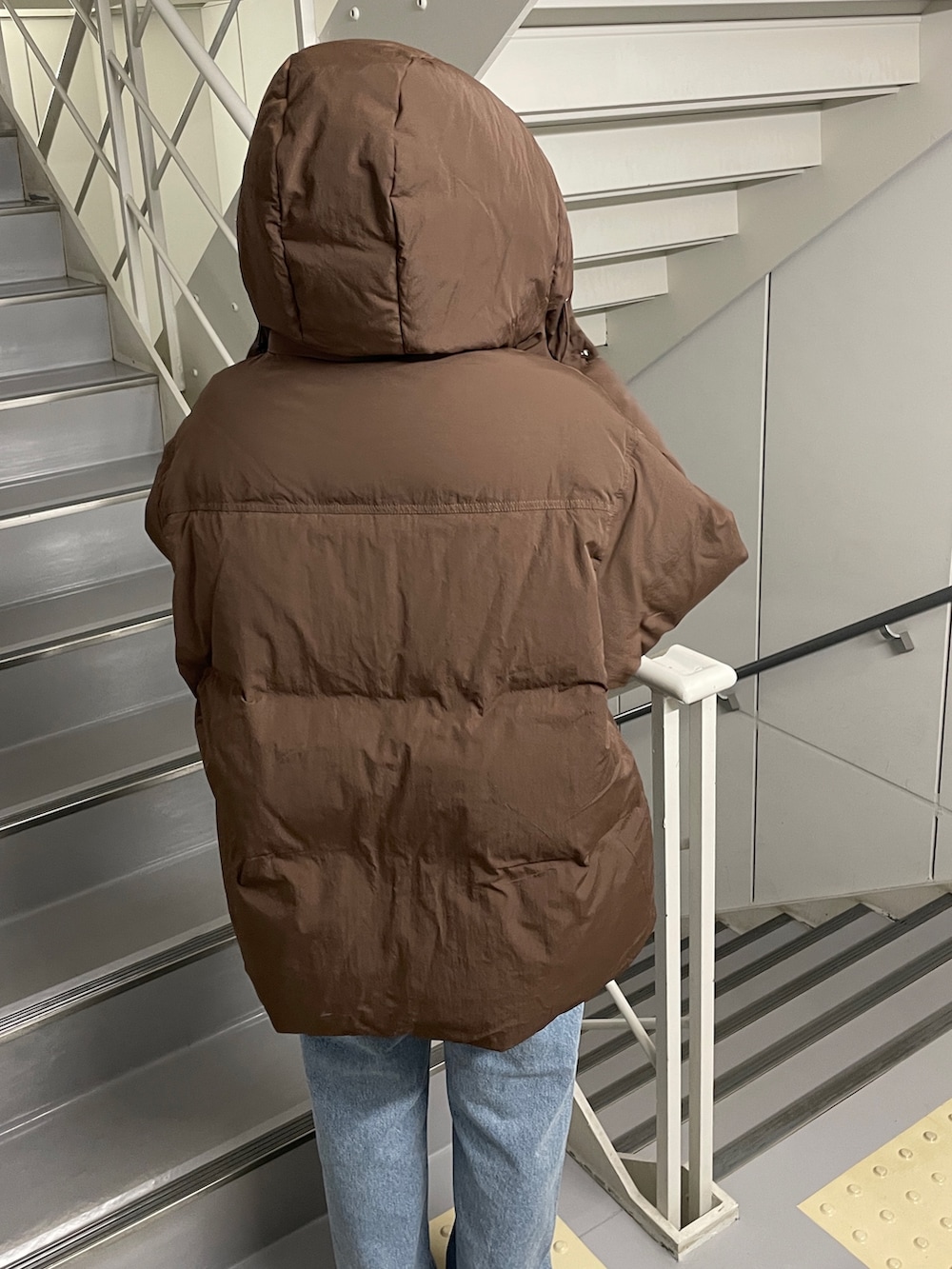 ブルー系のデニムパンツ、ブラック系のブーツ、ブラウン系のダウンジャケット/コートを着用したレディースの秋コーディネートの5枚目の写真