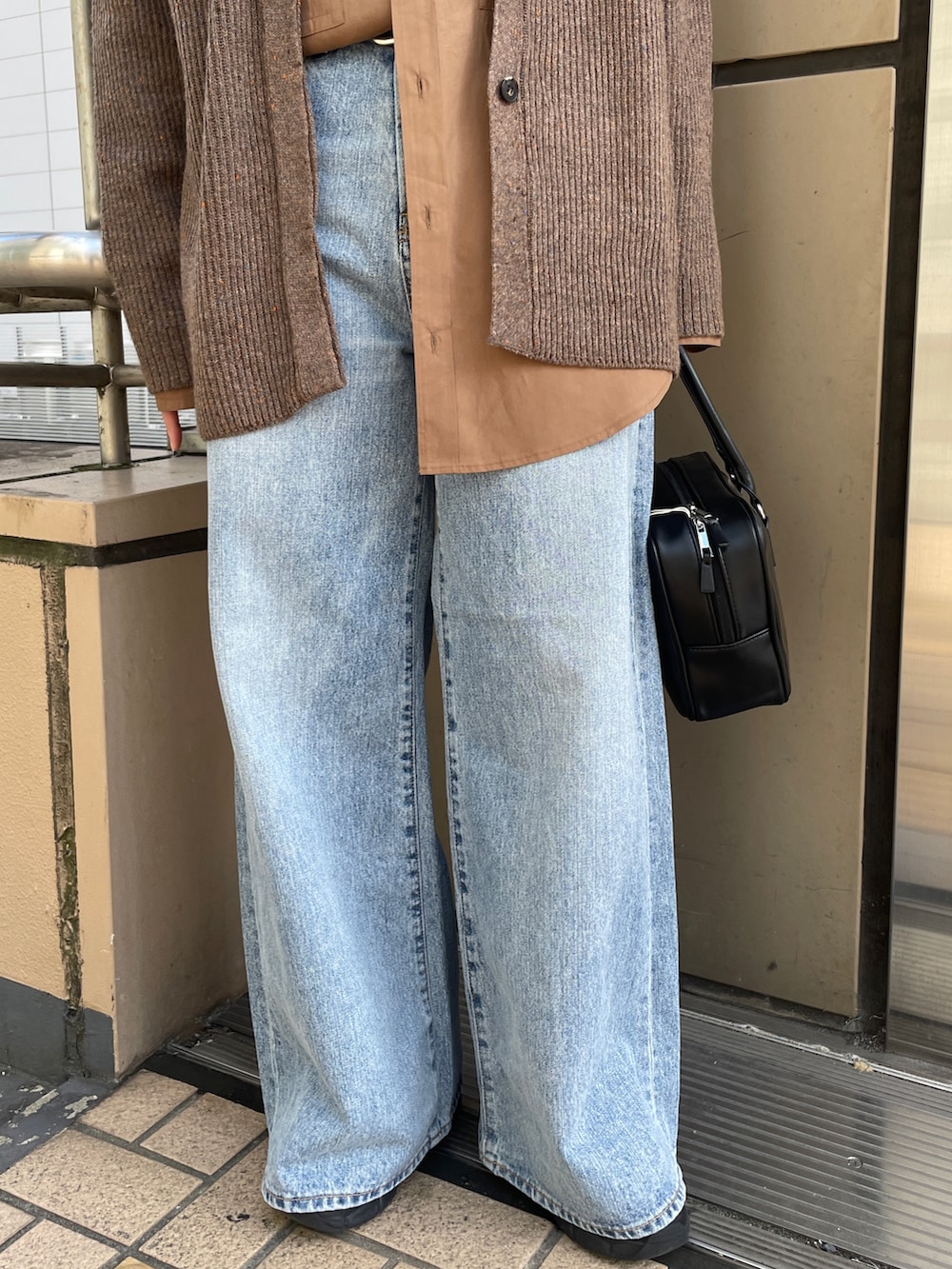 ブラウン系のカーディガン/ボレロ、ブルー系のデニムパンツ、ブラック系のハンドバッグを着用したレディースの秋コーディネートの7枚目の写真