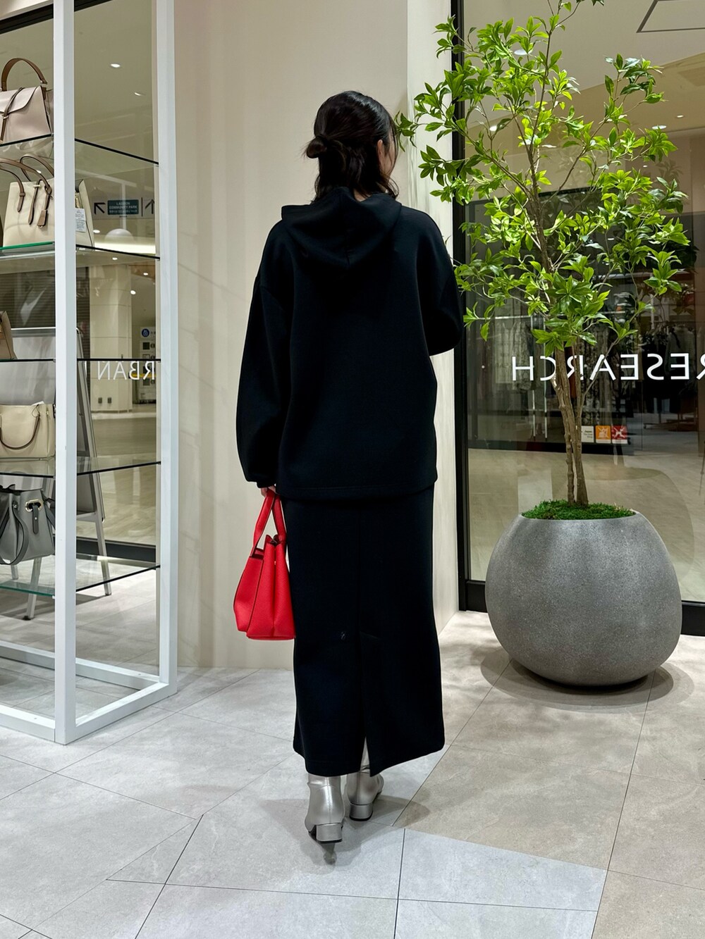 レッド系のトートバッグ、シルバー系のブーツ、ブラック系のワンピースを着用したレディースの冬コーディネートの4枚目の写真