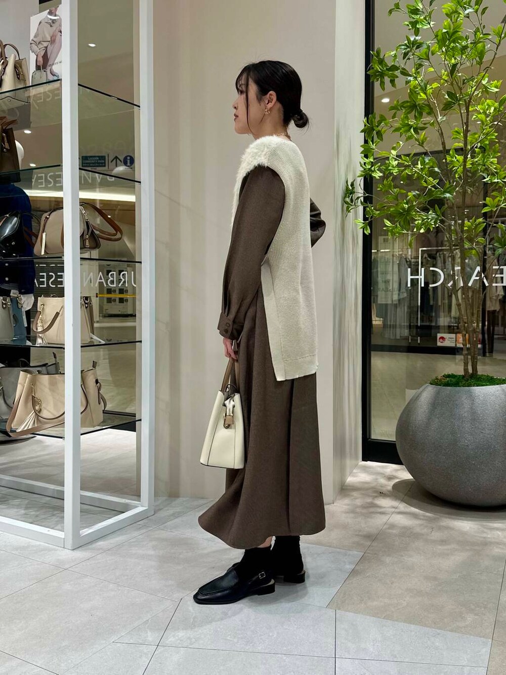 ホワイト系のトートバッグ、ブラック系のサンダル、ブラウン系のワンピースを着用したレディースの春コーディネートの3枚目の写真