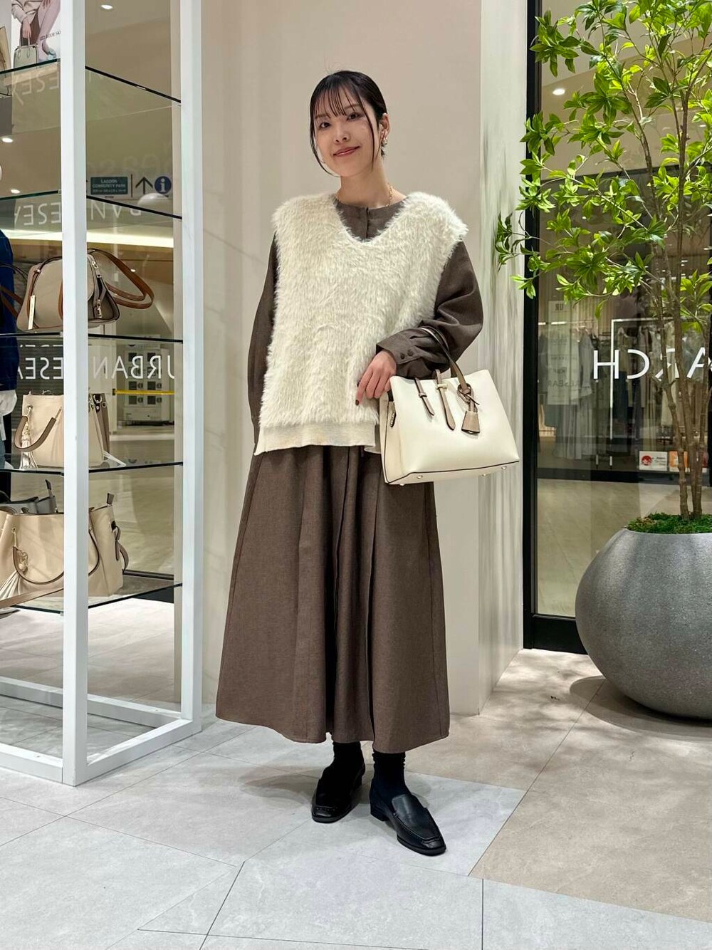 ホワイト系のトートバッグ、ブラック系のサンダル、ブラウン系のワンピースを着用したレディースの春コーディネートの2枚目の写真