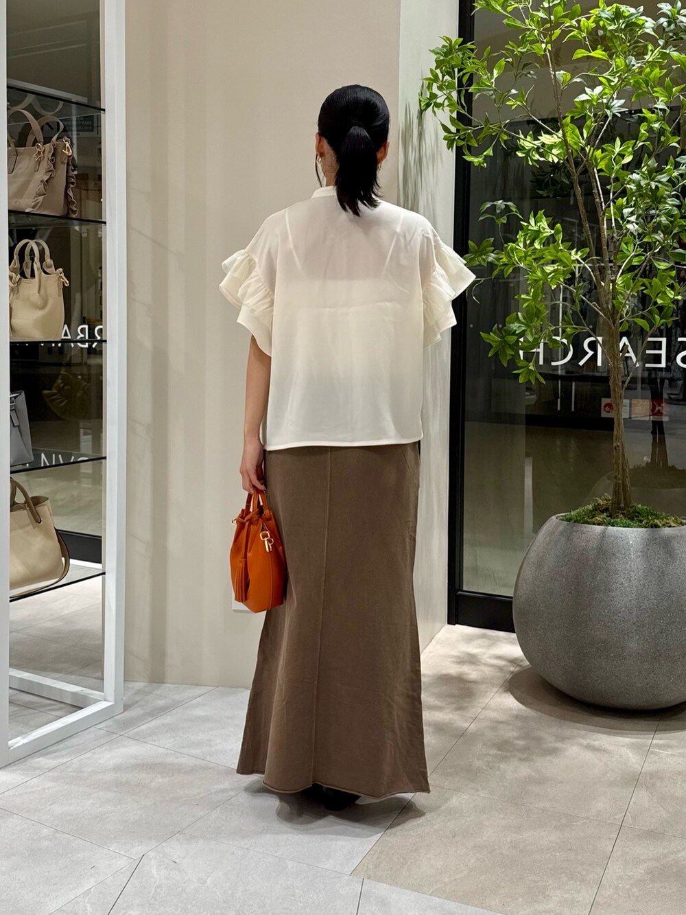 ホワイト系のシャツ/ブラウス、ブラウン系のスカート、オレンジ系のショルダーバッグを着用したレディースの秋コーディネートの4枚目の写真