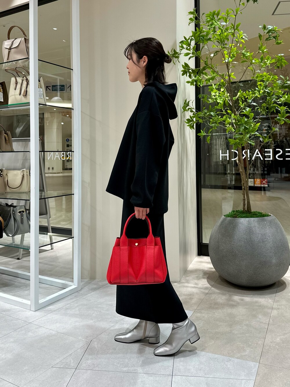 レッド系のトートバッグ、シルバー系のブーツ、ブラック系のワンピースを着用したレディースの冬コーディネートの3枚目の写真