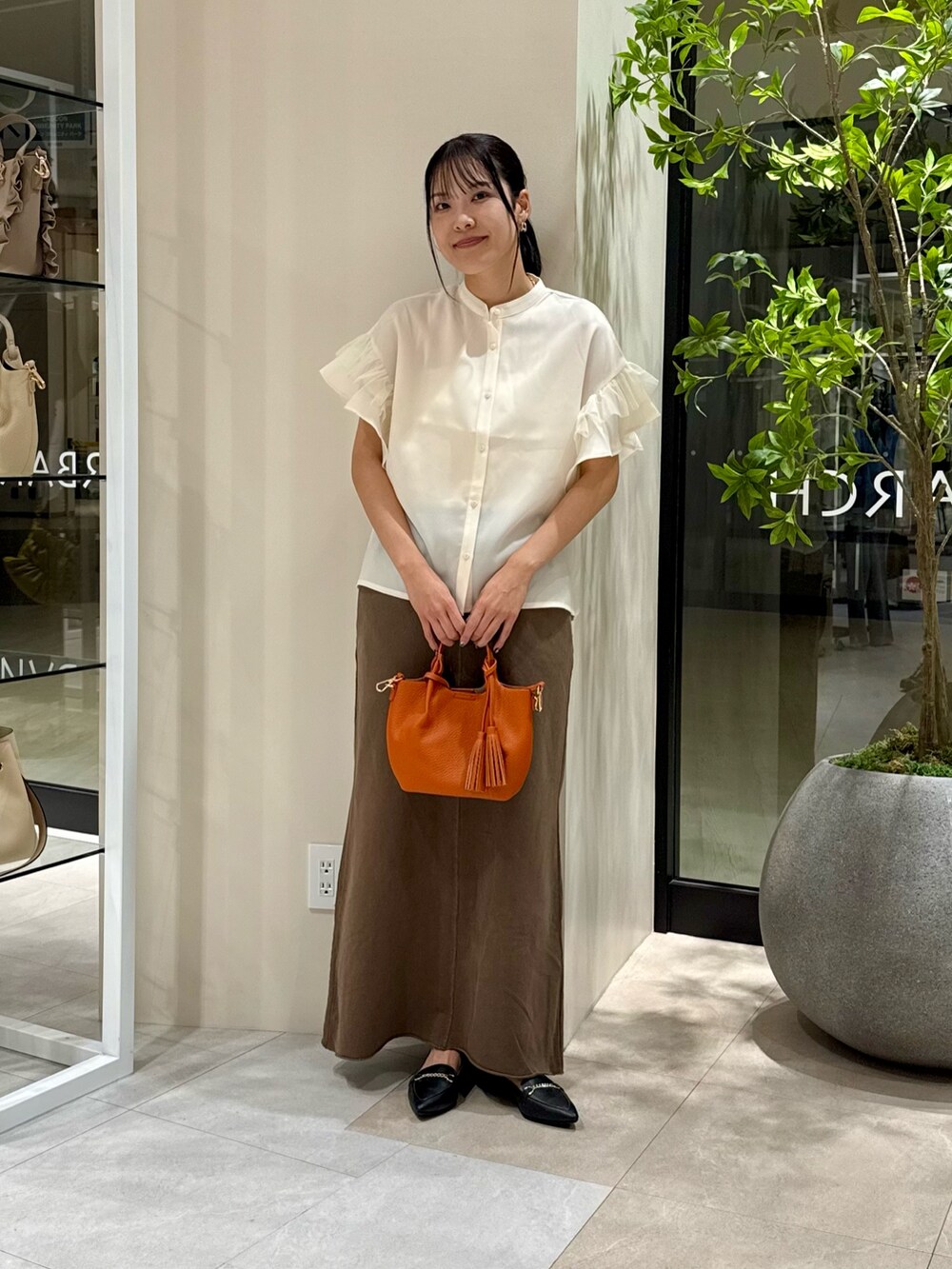 ホワイト系のシャツ/ブラウス、ブラウン系のスカート、オレンジ系のショルダーバッグを着用したレディースの秋コーディネートの2枚目の写真