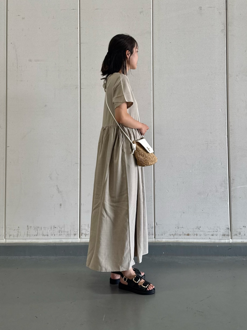 グレー系のワンピース、イエロー系のショルダーバッグ、ブラック系のサンダルを着用したレディースの夏コーディネートの3枚目の写真