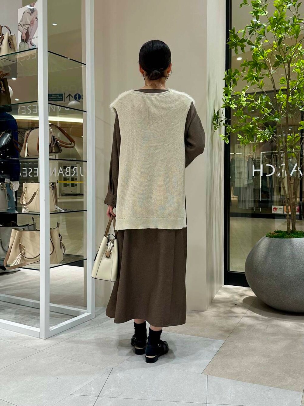 ホワイト系のトートバッグ、ブラック系のサンダル、ブラウン系のワンピースを着用したレディースの春コーディネートの4枚目の写真