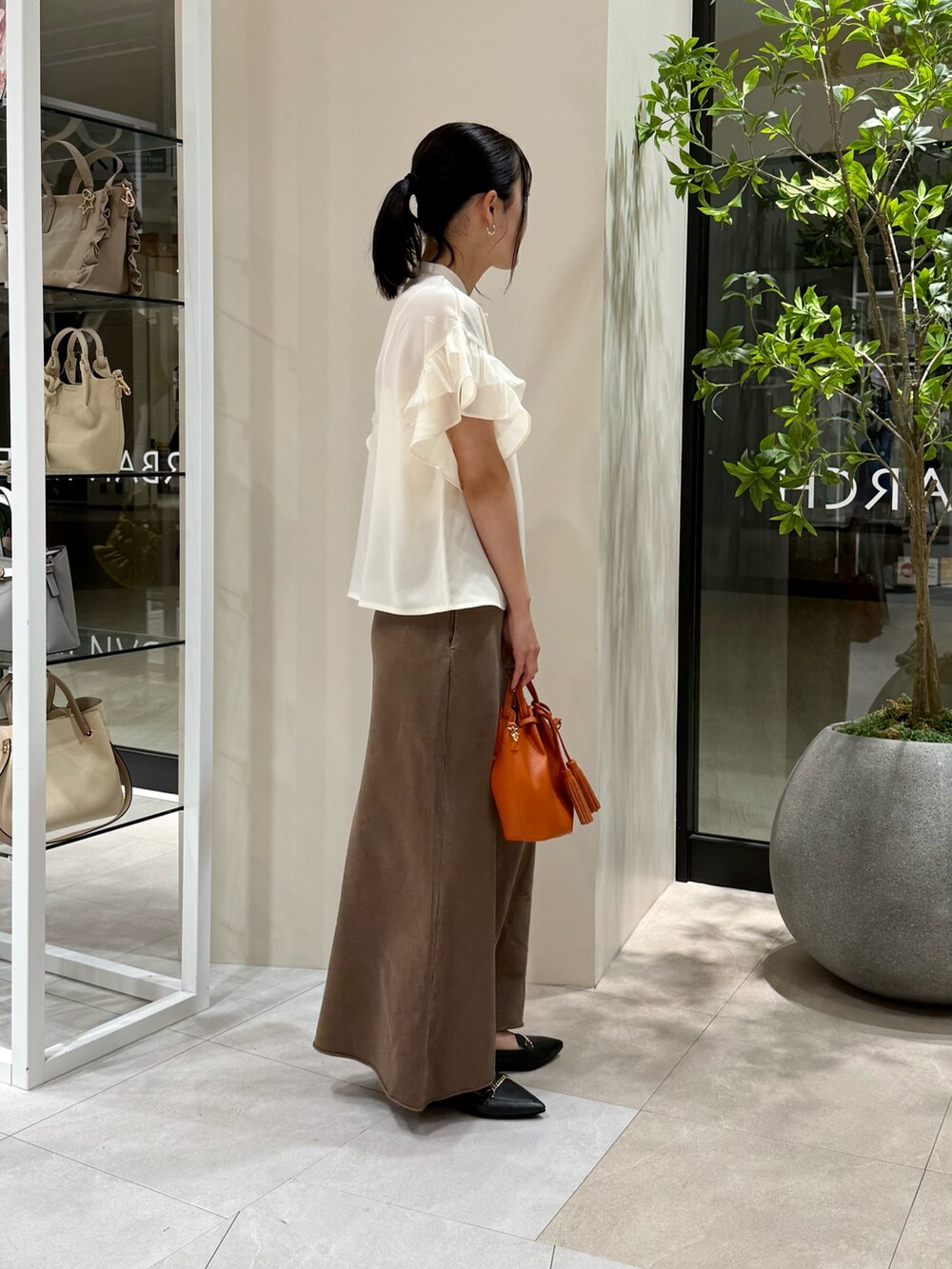 ホワイト系のシャツ/ブラウス、ブラウン系のスカート、オレンジ系のショルダーバッグを着用したレディースの秋コーディネートの3枚目の写真