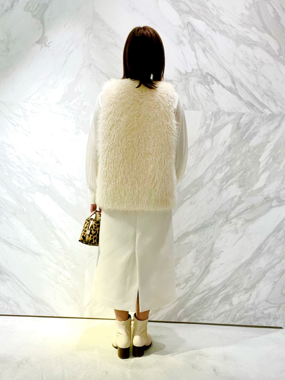 ベージュ系のバッグ、ホワイト系のその他アウター、ホワイト系のニット/セーターを着用したレディースの秋コーディネートの3枚目の写真