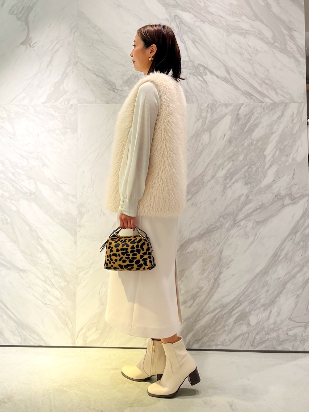 ベージュ系のバッグ、ホワイト系のその他アウター、ホワイト系のニット/セーターを着用したレディースの秋コーディネートの2枚目の写真