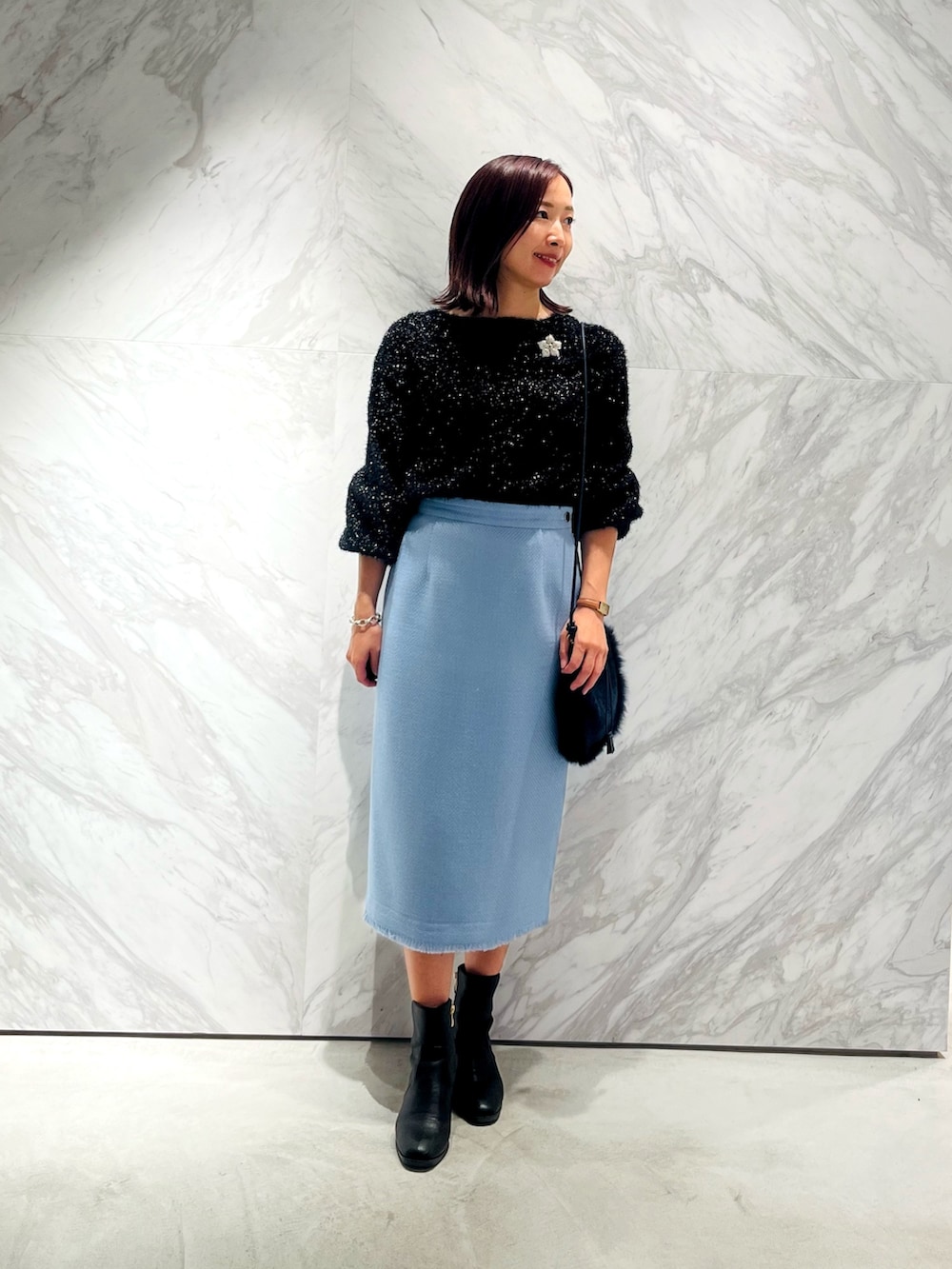 ブルー系のスカート、ブラック系のカーディガン/ボレロ、シルバー系のブローチ/コサージュを着用したレディースの秋コーディネートの2枚目の写真