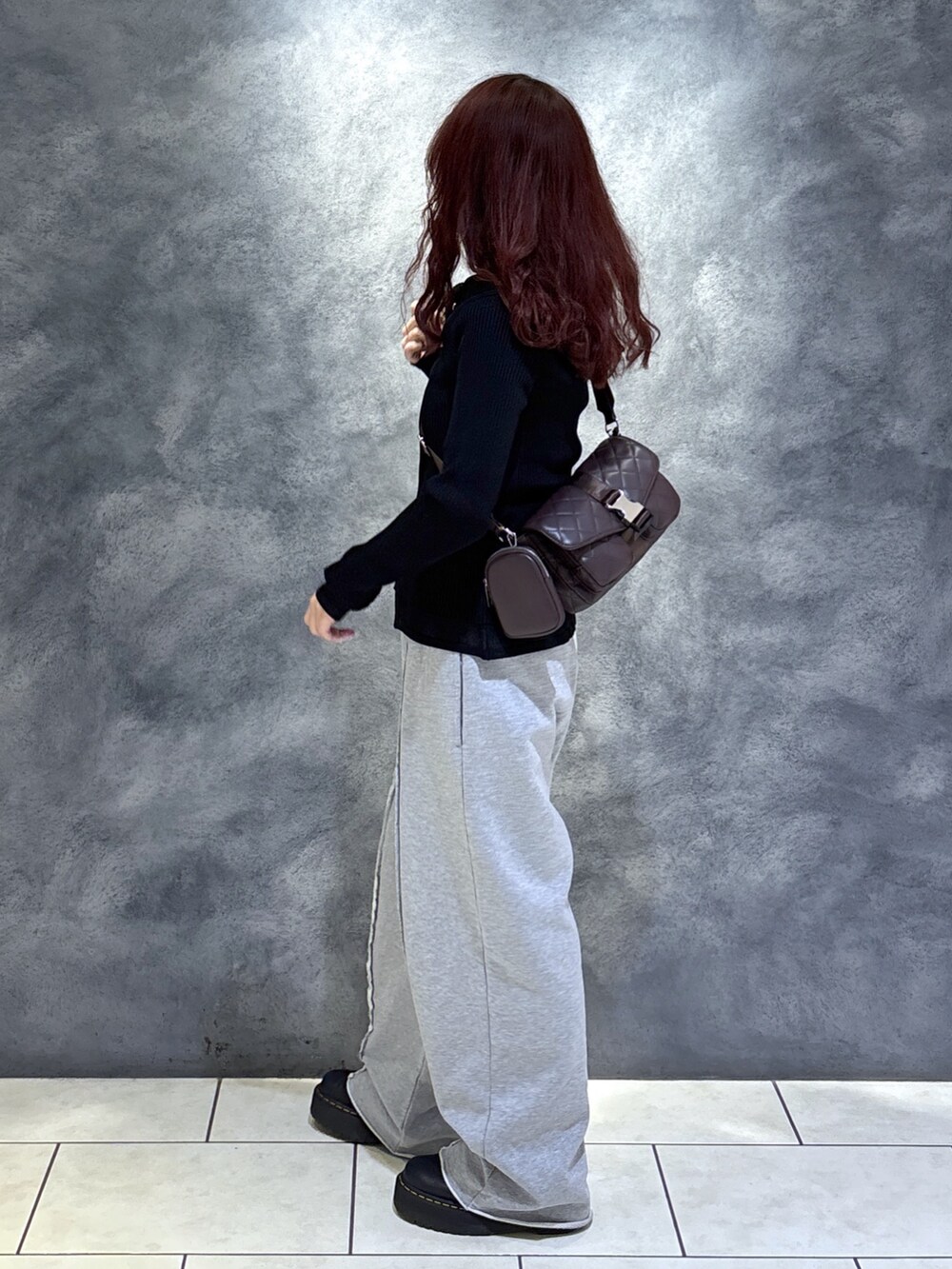 ブラック系のニット/セーター、ブラウン系のショルダーバッグ、ブラック系のブーツを着用したレディースの秋コーディネートの5枚目の写真