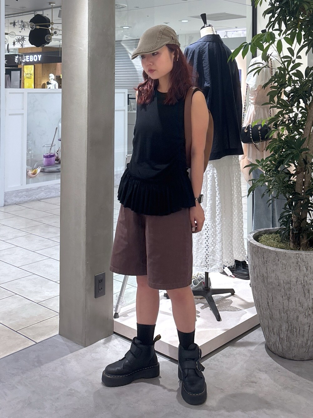 ブラウン系のデニムパンツ、ブラック系のブーツ、ブラック系のTシャツ/カットソーを着用したレディースの夏コーディネートの3枚目の写真