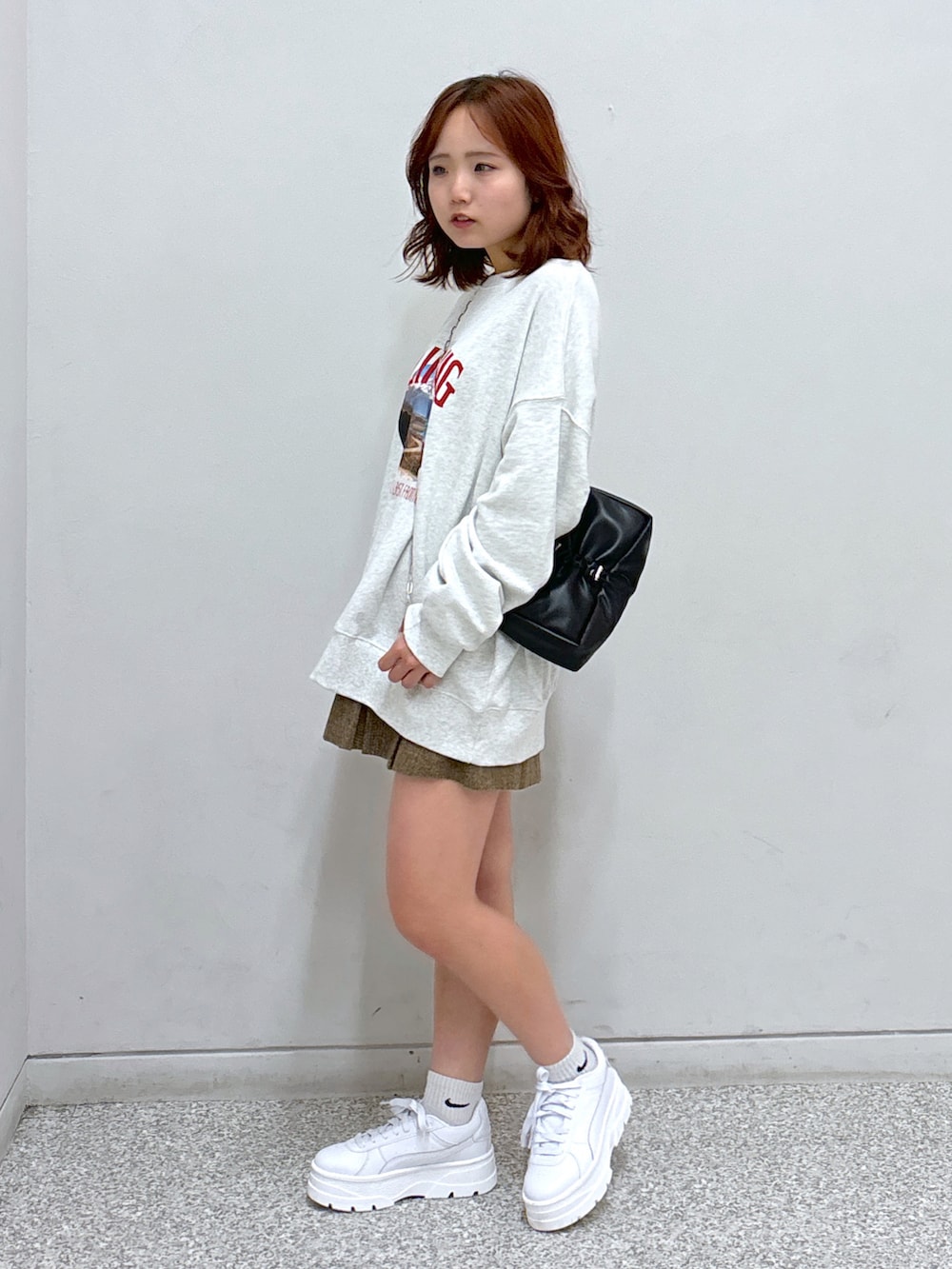 ホワイト系のスウェット、ブラウン系のスカート、ブラック系のハンドバッグを着用したレディースの秋コーディネートの3枚目の写真