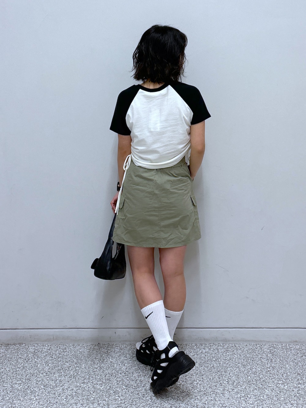 ブラック系のショルダーバッグ、ブラック系のサンダル、グリーン系のスカートを着用したレディースの春コーディネートの4枚目の写真