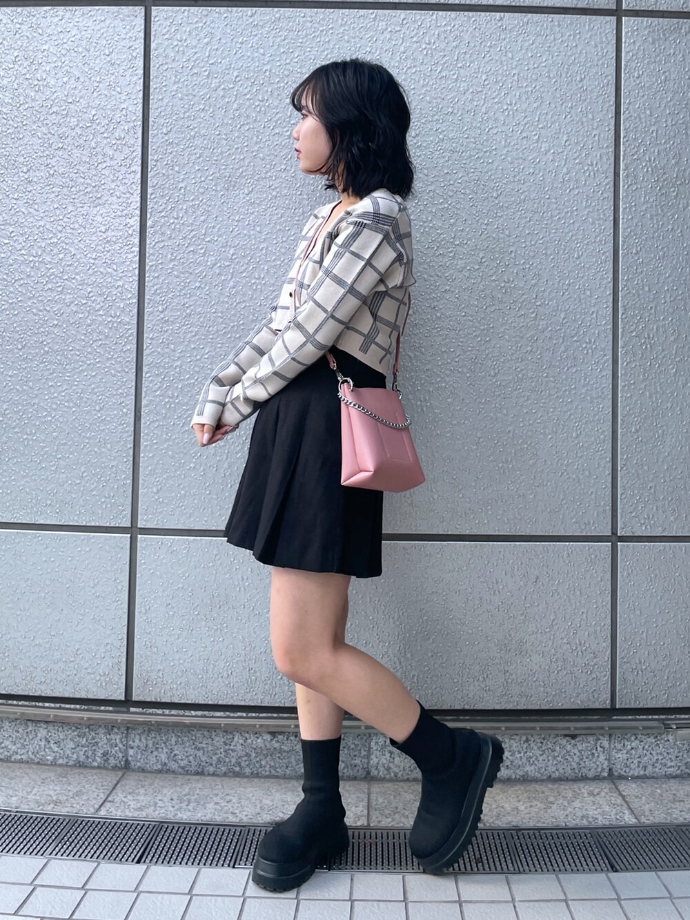 ブラック系のスカート、ホワイト系のニット/セーター、ピンク系のショルダーバッグを着用したレディースの冬コーディネートの2枚目の写真