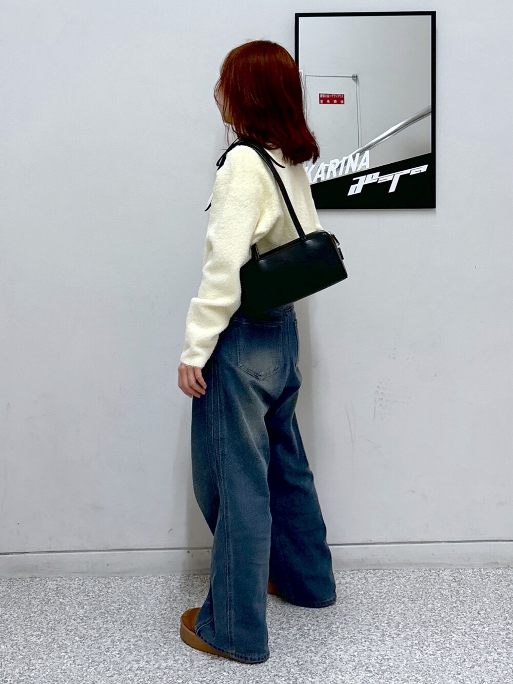 ホワイト系のカーディガン/ボレロ、ブラック系のショルダーバッグ、ブルー系のデニムパンツを着用したレディースの冬コーディネートの4枚目の写真