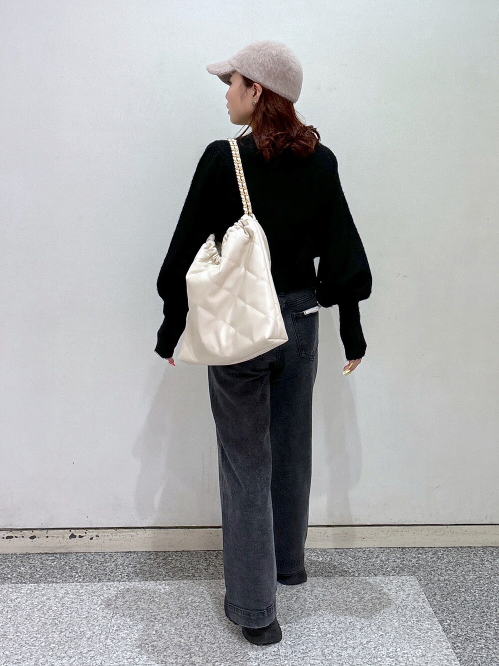 ブラック系のニット/セーター、ブラック系のデニムパンツ、ホワイト系のスニーカーを着用したレディースの冬コーディネートの5枚目の写真