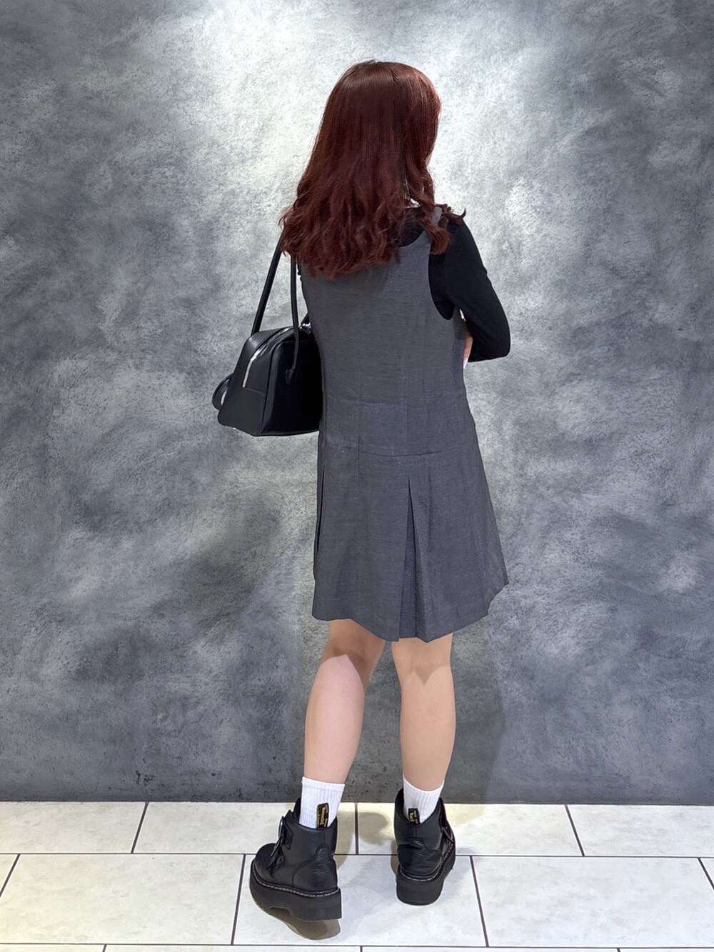 ブラック系のTシャツ/カットソー、ブラック系のブーツ、グレー系のジャンパースカートを着用したレディースの秋コーディネートの10枚目の写真