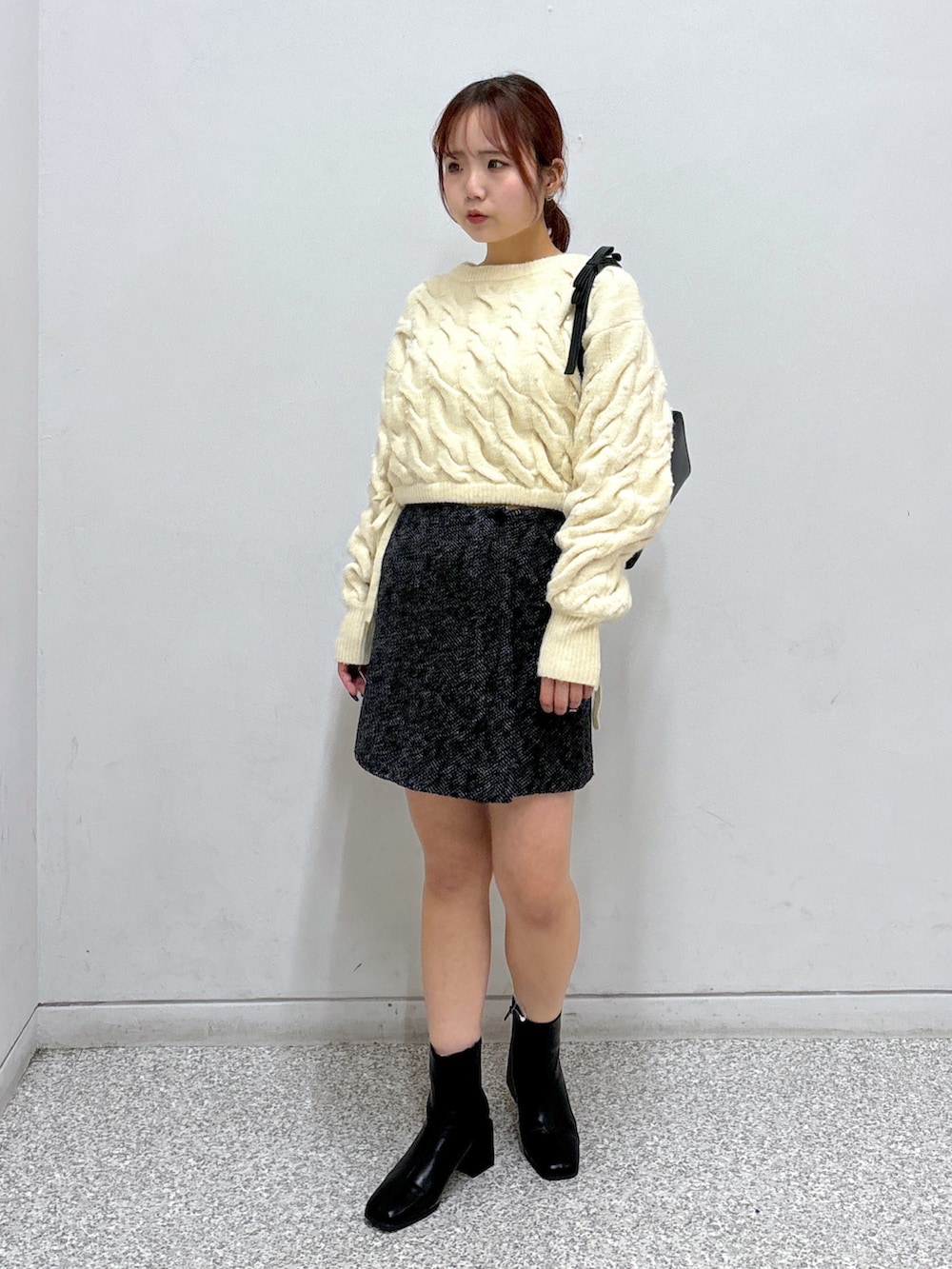 ホワイト系のニット/セーター、ブラック系のスカート、ブラック系のブーツを着用したレディースの冬コーディネートの3枚目の写真