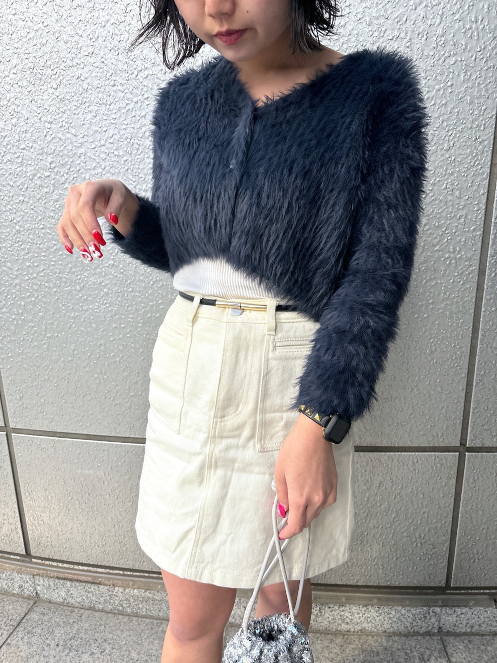 シルバー系のハンドバッグ、ブルー系のカーディガン/ボレロ、ホワイト系のスカートを着用したレディースの冬コーディネートの4枚目の写真