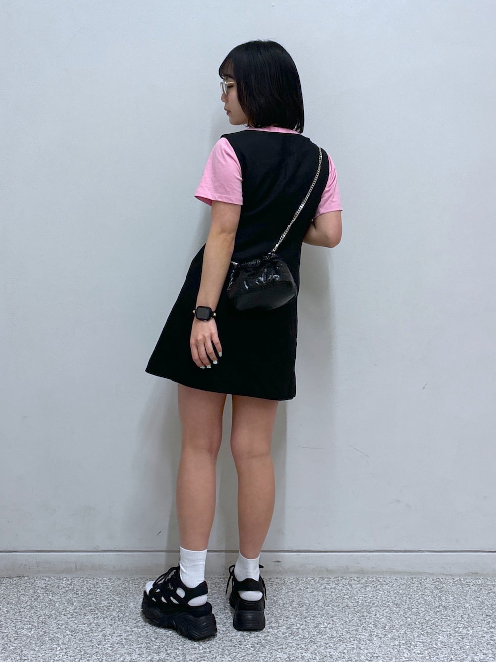 ブラック系のジャンパースカート、ブラック系のサンダル、ピンク系のTシャツ/カットソーを着用したレディースの春コーディネートの4枚目の写真