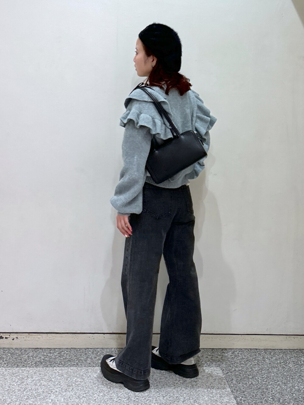 ブルー系のニット/セーター、ブラック系のデニムパンツ、ブラック系のショルダーバッグを着用したレディースの冬コーディネートの4枚目の写真