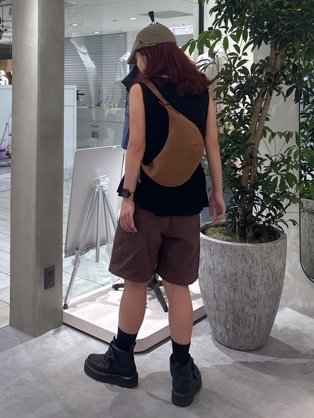 ブラウン系のデニムパンツ、ブラック系のブーツ、ブラック系のTシャツ/カットソーを着用したレディースの夏コーディネートの6枚目の写真