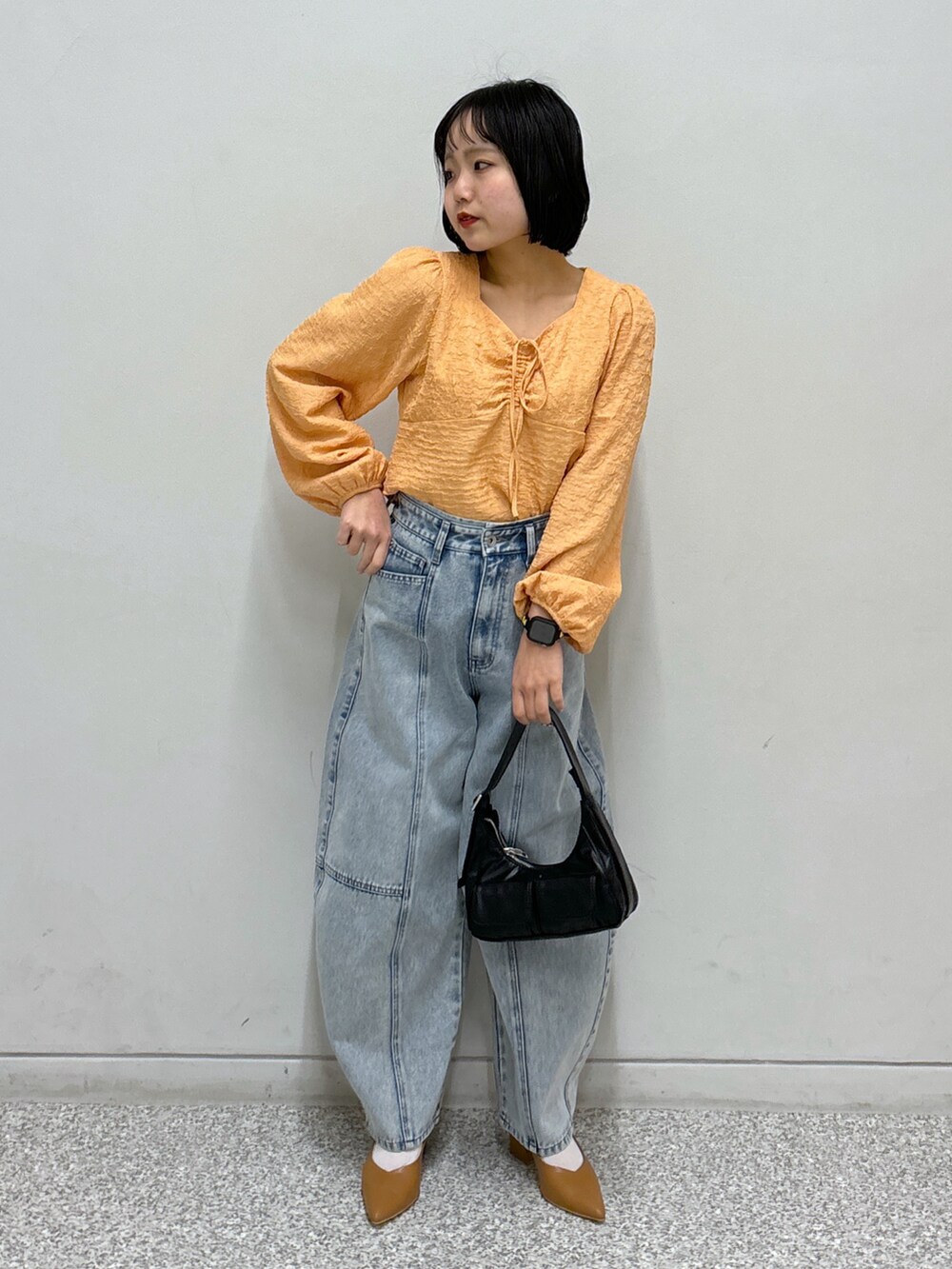 ブルー系のデニムパンツ、オレンジ系のシャツ/ブラウス、ベージュ系のパンプスを着用したレディースの春コーディネートの2枚目の写真