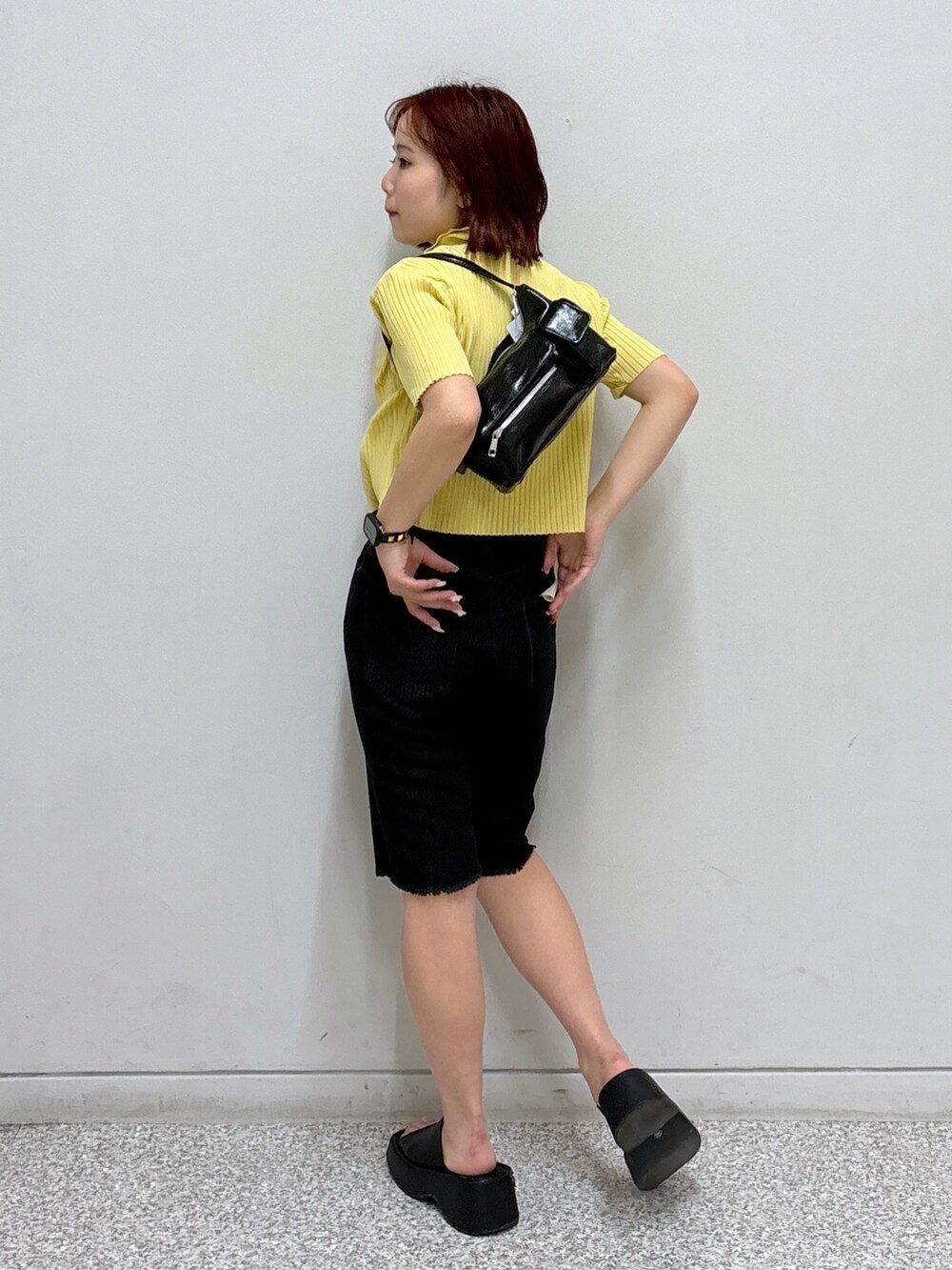イエロー系のニット/セーター、ブラック系のデニムパンツ、ホワイト系のハンドバッグを着用したレディースの夏コーディネートの3枚目の写真