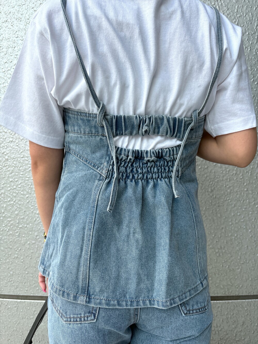 ブルー系のデニムパンツ、ブルー系のベスト、ホワイト系のTシャツ/カットソーを着用したレディースの春コーディネートの5枚目の写真