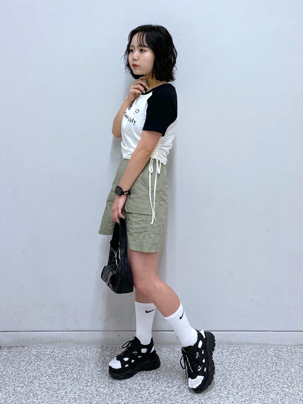 ブラック系のショルダーバッグ、ブラック系のサンダル、グリーン系のスカートを着用したレディースの春コーディネートの2枚目の写真