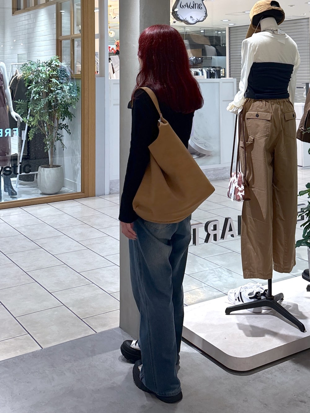 ブラック系のニット/セーター、ホワイト系のキャミソール、ブルー系のデニムパンツを着用したレディースの秋コーディネートの8枚目の写真