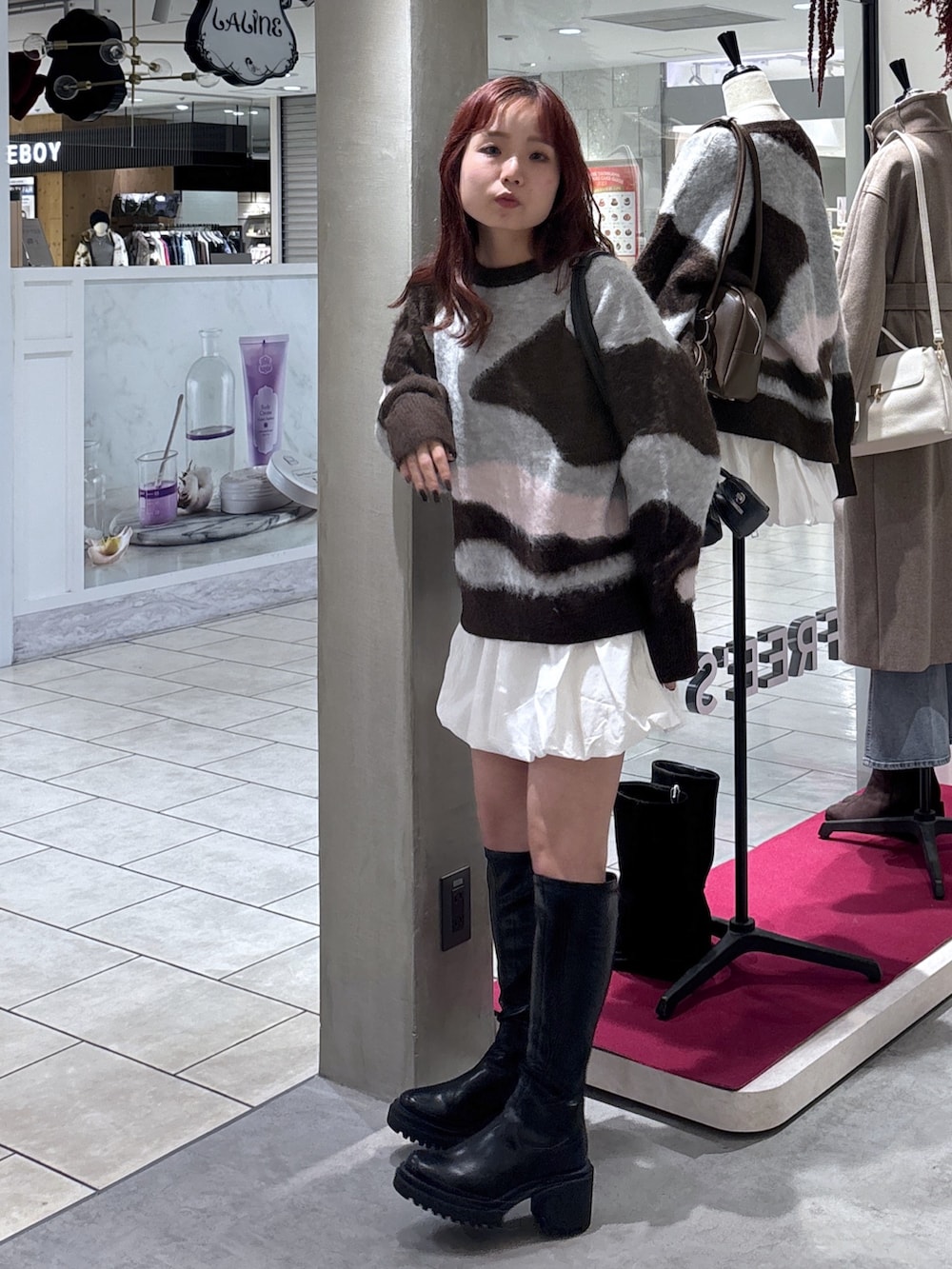 ホワイト系のスカート、ブラック系のブーツ、ブラック系のトートバッグを着用したレディースの冬コーディネートの6枚目の写真