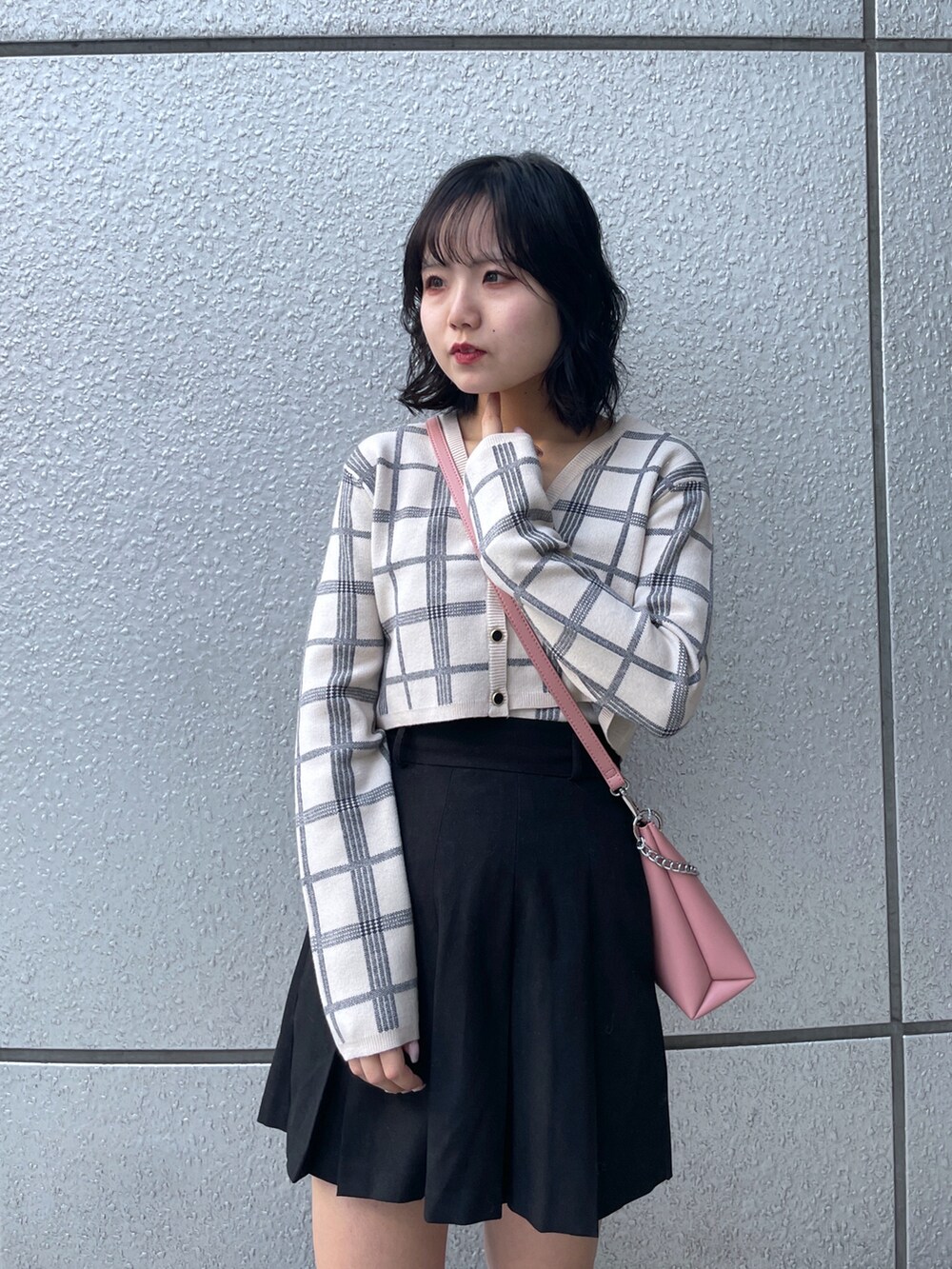 ブラック系のスカート、ホワイト系のニット/セーター、ピンク系のショルダーバッグを着用したレディースの冬コーディネートの4枚目の写真